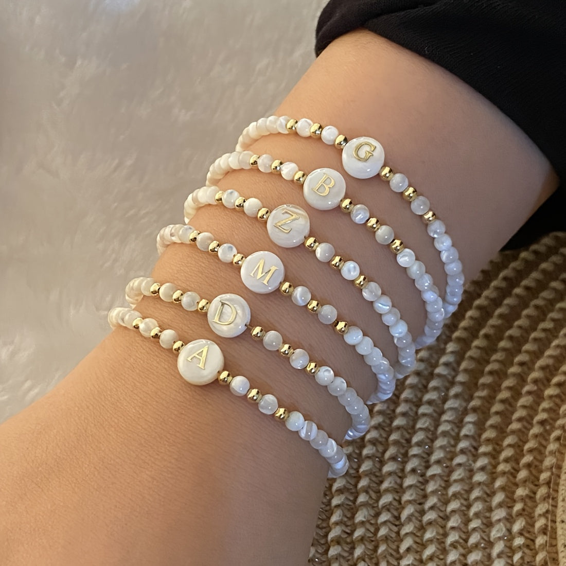 Several Elegant Initial Pearl Bracelets layered on the wrist