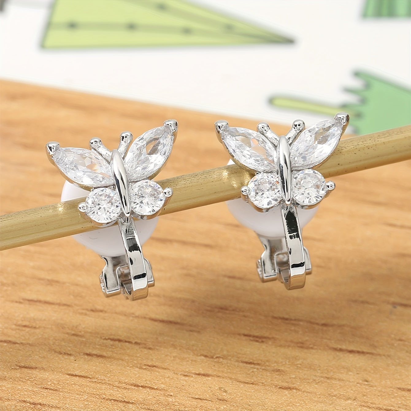 Elegant Zirconia Butterfly Clip Earrings on a wooden surface
